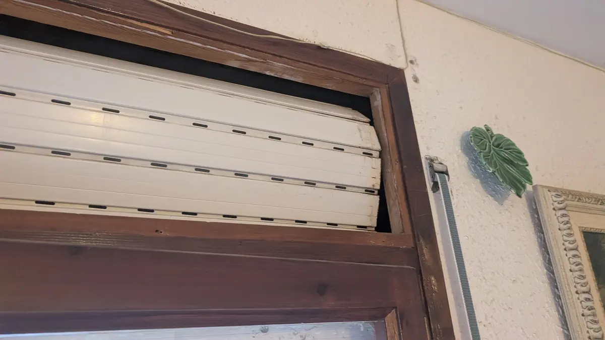 Cajón de persiana abierto en una ventana con marco de madera