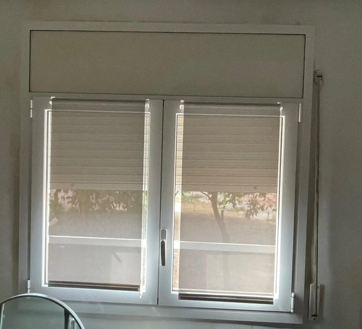Ventana de dos hojas con persiana clara instalada en una vivienda de Barcelona