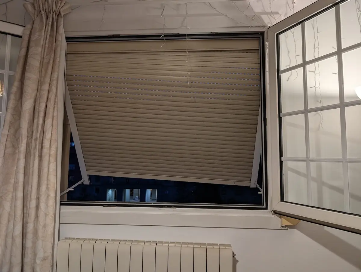 Ventana de habitación con la persiana beige bajada tras el montaje