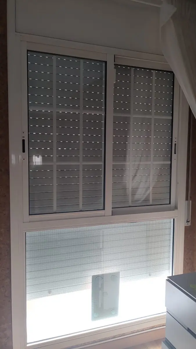 Ventana corredera con persiana microperforada oscura en una vivienda