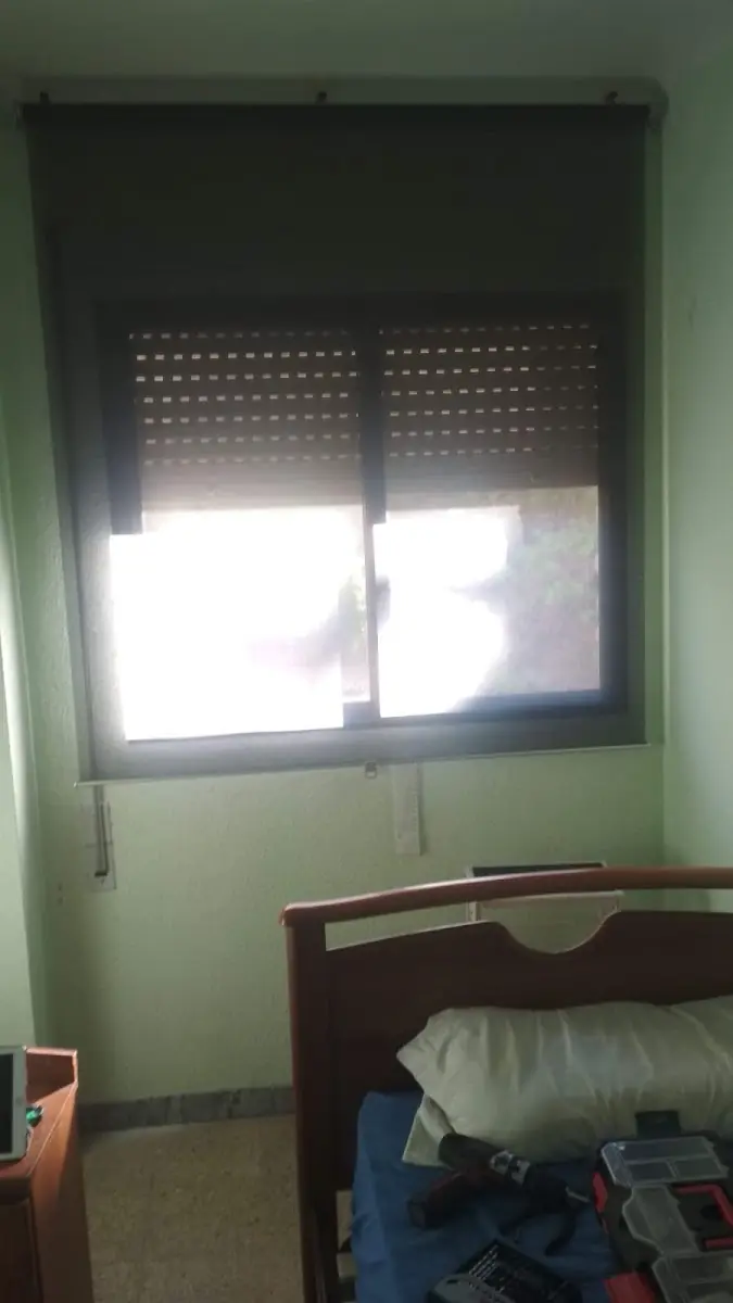 Persiana microperforada instalada en la ventana de un dormitorio