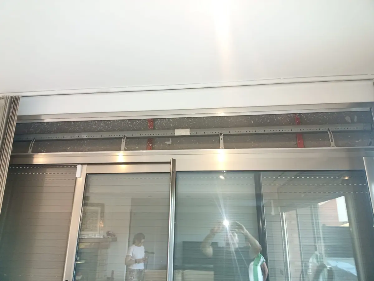 Montaje de una persiana sobre una puerta corredera, con el cajón a la vista