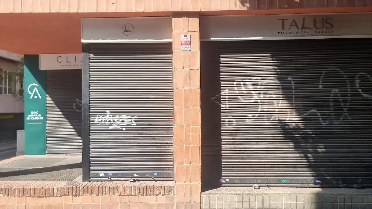 Dos locales comerciales de Barcelona con el cierre metálico bajado en horario de apertura